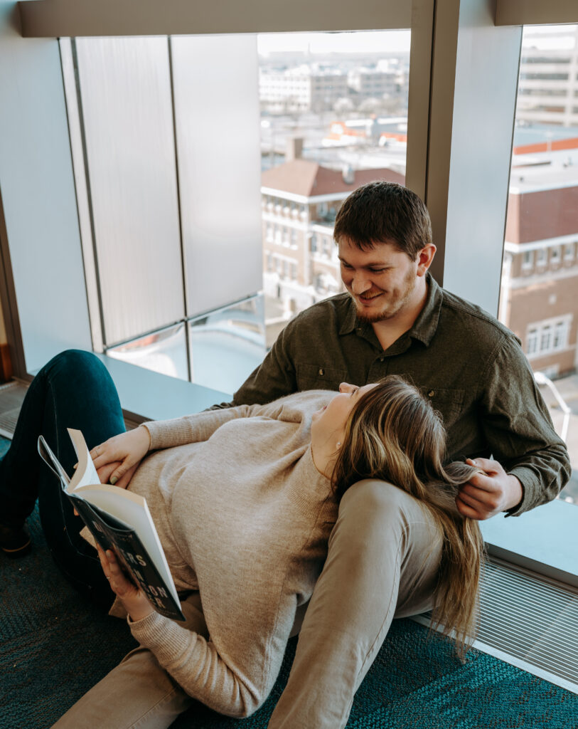 Couple posing infront of the window reading a library book