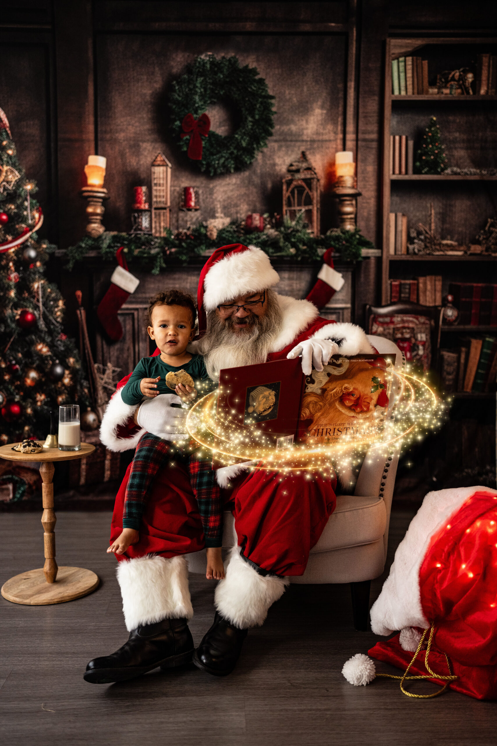 child eating a cookie on santas lap with magic around them infront of a christmas backdrop